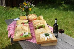 einem Picknicktisch mit Essen und einer Flasche Wein in der Unterkunft Löchle. Ferienhütte im Bregenzerwald, Andelsbuch in Andelsbuch