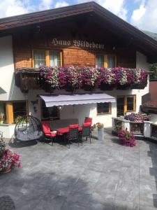 um edifício com um pátio com cadeiras vermelhas e flores em Haus Wildebene em Sankt Anton am Arlberg