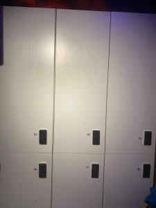a row of white lockers with cell phones on them at Sleep Cubee Hostel in Hong Kong