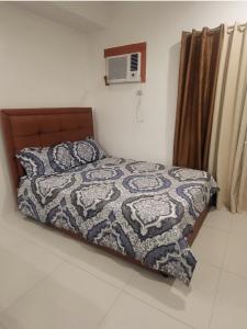 1 dormitorio con cama con edredón y almohadas en Spacious Minimalist Studio at Matina Enclaves en Davao