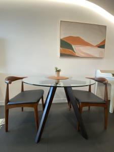 a glass table with two chairs and a table and a painting at Stylish Central Lake View Apartment in Canberra