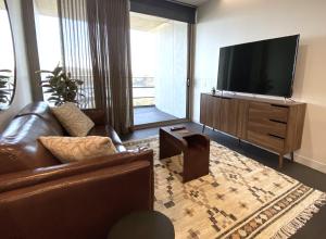 a living room with a couch and a flat screen tv at Stylish Central Lake View Apartment in Canberra