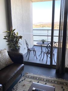 a living room with a couch and a table on a balcony at Stylish Central Lake View Apartment in Canberra