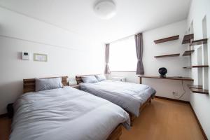 two beds in a small room with a window at THE VILLA FURANO【Wide Horizon】 in Furano