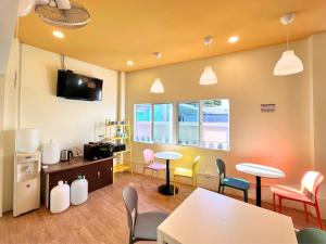 a waiting room with tables and chairs and a tv at Sleepy Station Hostel in Kata Beach