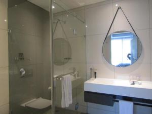 uma casa de banho com um chuveiro, um lavatório e um espelho. em 1 Bedroom Luxury Apartment in Luxury Hotel & Apartments in Sandton Central em Joanesburgo