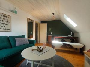 a living room with a green couch and a table at De Dackluuk in Wittmund