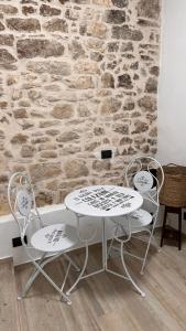 two chairs and a table in front of a stone wall at Dimora la Motta in Modugno