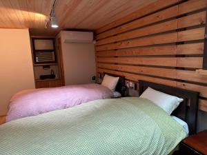 two beds in a room with wooden walls at 銅の夢 in Ōmama