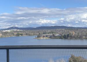 a view of a large lake with a building and akson at Stylish Central Lake View Apartment in Canberra
