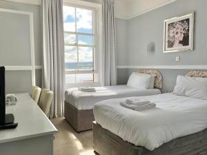 a hotel room with two beds and a window at Ashton Court Hotel in Exmouth