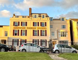 エクスマウスにあるAshton Court Hotelの車が目の前に停まった黄色い建物