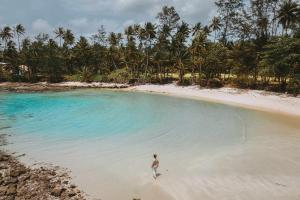 a man standing in the water on a beach at Hideout Koh Kood in Ko Kood