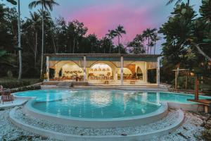 a pool at a resort with a sunset in the background at Hideout Koh Kood in Ko Kood