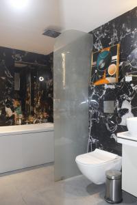 baño con aseo y pared negra en LUXUS INN, en Dhanbād