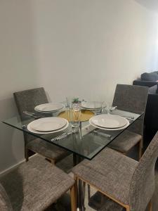 una mesa de cristal con 4 sillas y platos. en Best hotel Leicester city en Leicester