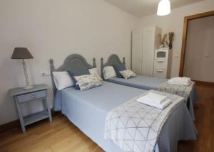 a bedroom with two beds and a table with a lamp at Apartamento Buruntzali in Elizondo