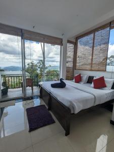 a bedroom with a large bed and large windows at Nilowin Glenanore Guesthouse in Haputale