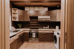 a kitchen with wooden cabinets and a washer and dryer at Holiday home Migliņas in Kaugurmuiza