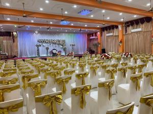 a banquet hall with white chairs and gold bows at Hotel Juli Reception in Mannar