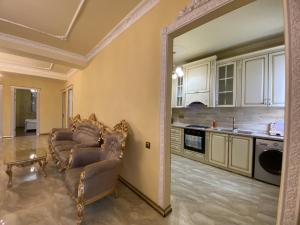 a living room with two chairs and a kitchen at AL SHEIKH 5 BEDROOM LUXURY APARTMENT 1 in Yerevan