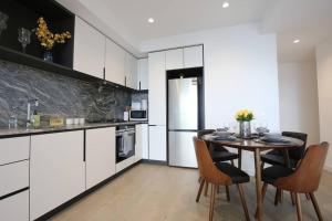 eine Küche mit weißen Schränken sowie einem Tisch und Stühlen in der Unterkunft Brand New 2BR Apt at Mel CBD in Melbourne