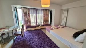 a bedroom with two beds and a desk and a window at Ris studio dublu universitate, centrul vechi in Bucharest