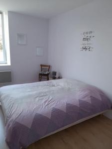 een slaapkamer met een bed met een paars dekbed bij En passant par La Maraude in Vigneulles-lès-Hattonchâtel