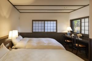 a bedroom with two beds and a desk and windows at Yufuin Yufusaryo in Yufuin