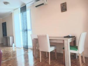 comedor con mesa de madera y sillas blancas en Comfort Apartment en Novi Beograd