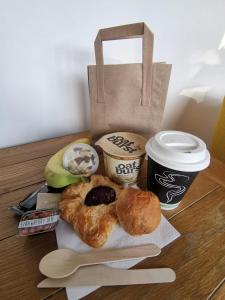 una mesa con un bagel una taza de café y dos donuts en Featherbed Cottage, en Coventry