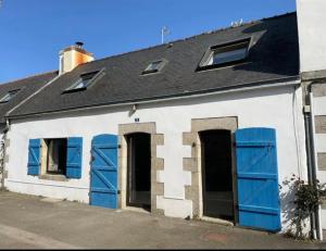 a white building with blue shutters and a roof at Maison de pêcheur BORD DE MER bois et pierre 6-8 pers in Plobannalec-Lesconil