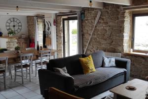 a living room with a couch and a brick wall at Maison de pêcheur BORD DE MER bois et pierre 6-8 pers in Plobannalec-Lesconil