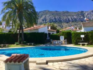 ein Schwimmbad in einem Garten mit Bergen im Hintergrund in der Unterkunft Casa de 2 dormitorios con piscina, 2 terrazas privadas, WIFI, BBQ in Denia