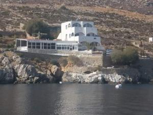 a white building on a hill next to a body of water at Kazonis Studios in Kalymnos