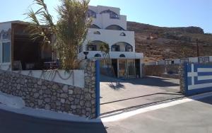 a large white building with a stone wall at Kazonis Studios in Kalymnos