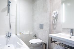 La salle de bains est pourvue de toilettes, d'un lavabo et d'une douche. dans l'établissement Hotel De La Digue, au Mont-Saint-Michel