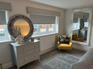 a bedroom with a mirror and a dresser and a chair at Stunning Beachfront Apartment in Cleethorpes