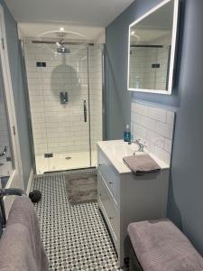 a bathroom with a sink and a shower with a mirror at Stunning Beachfront Apartment in Cleethorpes