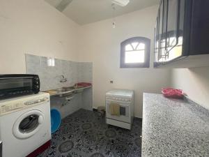 a kitchen with a washing machine and a sink at Gîte Hôtel Gezira Louxor in Luxor