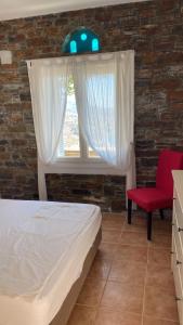 a bedroom with a bed and a window with a red chair at andros prive suites in Kipri