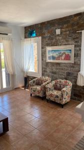 a living room with two chairs and a brick wall at andros prive suites in Kipri