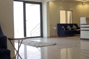 Durat Alnakheel Serviced Apartments في عنيزة: غرفة معيشة مع أريكة زرقاء وطاولة