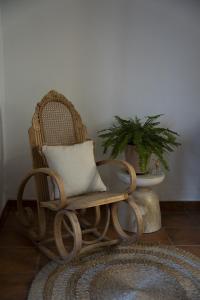 a wicker rocking chair with a pillow and a plant at Casa de pueblo Ca Barret, a tan sólo dos kilómetros de Xàtiva 
