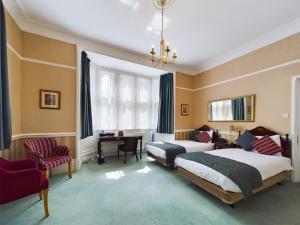 a hotel room with two beds and a desk at Beech House Hotel in Reading