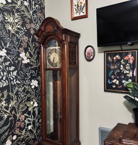 a grandfather clock against a wall with a floral wallpaper at Mr. McGregor’s Garden in Salem