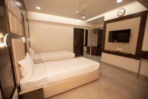 a hotel room with two beds and a tv at Hotel Naaz Executive in Mumbai