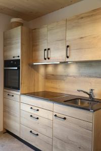 a kitchen with wooden cabinets and a sink and a microwave at Szapary 1620 in Woppendorf