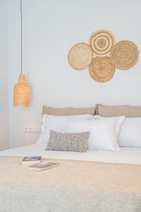 a bed with white pillows and hats on the wall at Disis Residence in Naxos Chora
