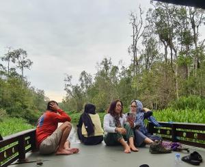 a group of people sitting on a boat in a river at Orangutan Houseboat Park Tanjung Puting in Pangkalan Bun